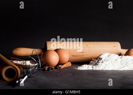 Zutaten wie Eiern, Mehl, Zimt, Anis, Nudelholz, Papier auf Tafel Stockfoto