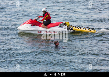 RNLI Rettungsschwimmer Jetski mit Rettungsschwimmer und Mann im Meer am Bournemouth Beach, Bournemouth, Dorset UK an einem warmen sonnigen Tag im Mai Stockfoto