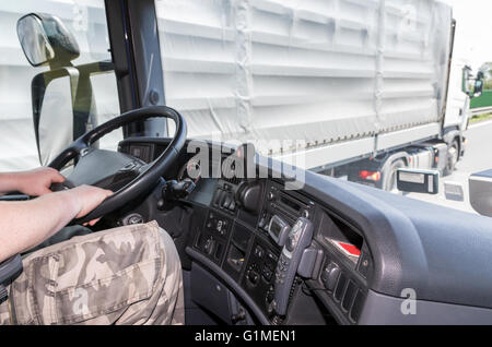 Blick von der LKW-Kabine für den Fahrer, der das Lenkrad hält. Der Truck ist gerade von einem anderen LKW überholt. Stockfoto