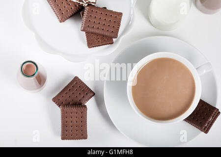 Tasse Kaffee und einige Flaschen Milch und Schokolade Milchshakes auf weißem Hintergrund von oben Stockfoto