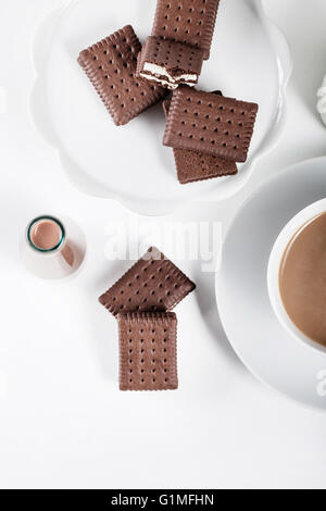 Tasse Kaffee und einige Flaschen Milch und Schokolade Milchshakes auf weißem Hintergrund von oben Stockfoto