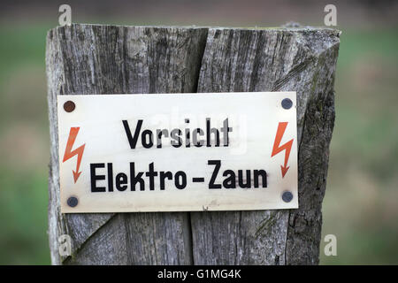 Zeichen sagen: Vorsicht, Elektrozaun. Stockfoto