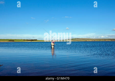 Fliegenfischen Sie auf Colliford Stausee Lake Bodmin Moor Cornwall einsamen Mann casting mit Stab auf noch See blauer Himmel Stockfoto