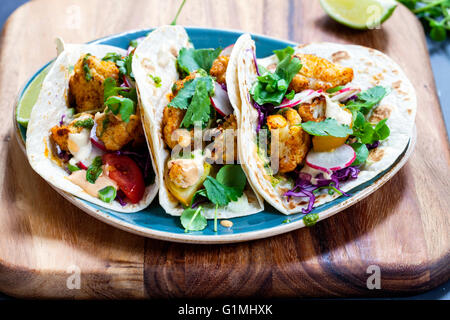 Blumenkohl-Tacos mit Rotkohl, Radieschen, Tomaten, Frühlingszwiebeln, Tahini-Sauce und Chipotle Soße zu braten Stockfoto