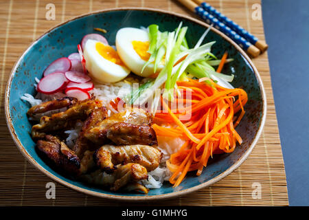 Gegrillte Hähnchenschenkel mit Reis und eingelegte Karotten, Zwiebeln und Radieschen Stockfoto