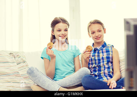 glückliche Mädchen vor dem Fernseher und Cookies zu Hause essen Stockfoto