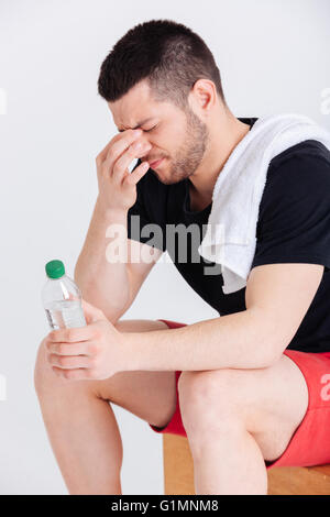 Müde Sportler halten Flasche mit Wasser isoliert auf weißem Hintergrund Stockfoto