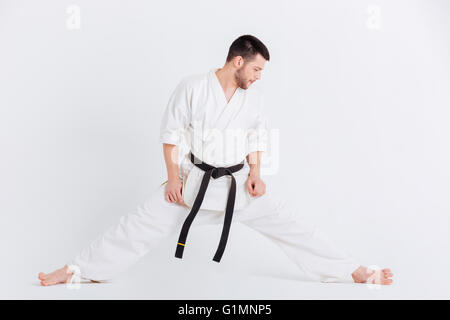 Voller Länge Porträt eines Mannes im Kimono stretching Übungen isoliert auf weißem Hintergrund Stockfoto