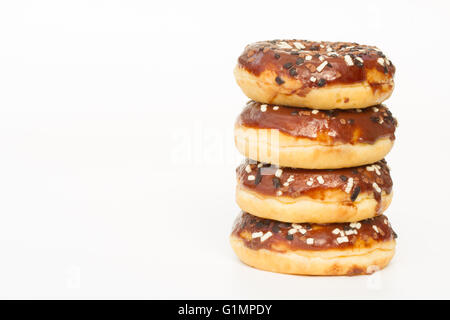 Ein Stapel von Krapfen mit Schokoladenglasur und Streuseln auf einem weißen Hintergrund. Stockfoto