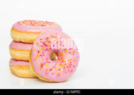 Ein Stapel von Donuts mit rosa Glasur und Streuseln auf einem weißen Hintergrund. Stockfoto