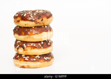 Ein Stapel von Krapfen mit Schokoladenglasur und Streuseln auf einem weißen Hintergrund. Stockfoto