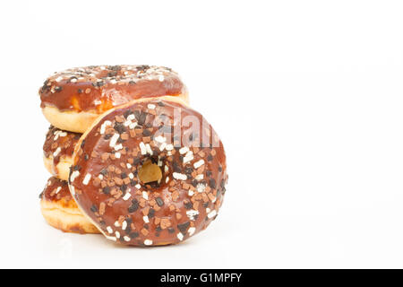 Ein Stapel von Krapfen mit Schokoladenglasur und Streuseln auf einem weißen Hintergrund. Stockfoto