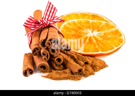 Getrocknete Orangenscheiben mit Zimtstangen und Zimtpulver auf weiß. Stockfoto