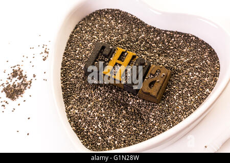 Gesunden Chia-Samen in eine herzförmige Schüssel auf einem weißen Hintergrund. Stockfoto