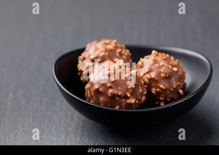 Pralinen, Trüffel in schwarzen Keramikschale auf grauem Schiefer Hintergrund Textfreiraum. Stockfoto