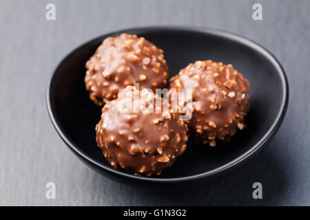 Pralinen, Trüffel in schwarzen Keramikschale auf grauem Schiefer Hintergrund Textfreiraum. Stockfoto