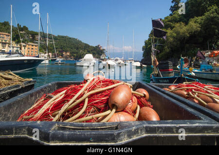 Portofino, Provinz Genua, Ligurien, italienische Riviera, Italien.  Fischernetze mit Hafen und Boote hinter. Stockfoto