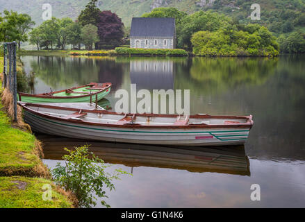 Gougane Barra, County Cork, Irland.  Eire.  Blick über Ruderboote vertäut am Ufer Sees mit der Eremitage Stockfoto