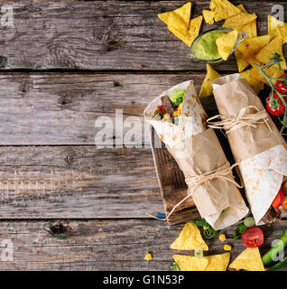 Abendessen im mexikanischen Stil. Zwei tapezierte Tortillas Burrito mit Rindfleisch und Gemüse serviert mit Gemüse, Nachos Chips und guacomole Stockfoto