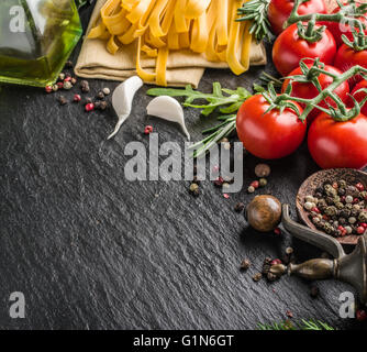 Pasta Zutaten. Cherry-Tomaten, Spaghetti Nudeln, Rosmarin und Gewürze auf einem Graphit-Brett. Stockfoto