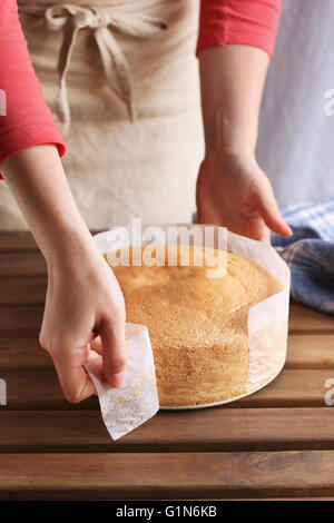 Weibliche Hände schälen des Pergament-Papiers von den Seiten von den Biskuit. Stockfoto