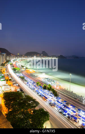 Sonnenuntergang am Strand von Copacabana, Ansicht von oben Copacabana Promenade (Calcadao) mit Zuckerhut im Hintergrund - Straße Verkäufer Zelte, wo man allerlei Ware kaufen kann. Die Promenade ist ein Pflaster Landschaft in großem Maßstab (4 Kilometer lang) mit einem schwarzen und weißen portugiesischen Schichtenaufbau von Roberto Burle Marx, eine geometrische Welle. Rio De Janeiro, Brasilien. Stockfoto