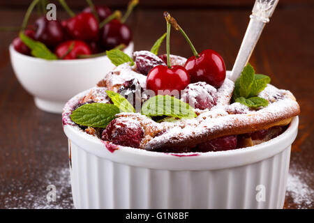 Französische Clafoutis mit Kirsche in Keramik Förmchen auf rustikalen Holztisch Stockfoto