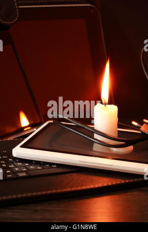 Blackout-Konzept. Licht Kerze auf Laptop und tablet Stockfoto