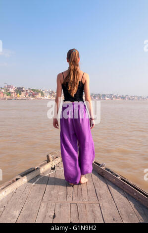 Junge, weibliche Praktizierende stehende Yoga Meditation auf dem Boot über den Fluss Ganges, Indien Stockfoto