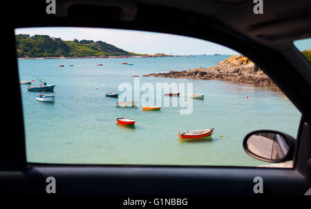 Einzigartige Aussicht aus einem Autofenster von einem malerischen Strand mit Fischerbooten in Guernsey, Channel Island. Stockfoto