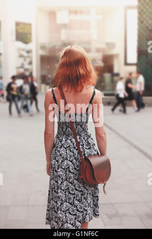 Eine junge Frau trägt eine Kleid ist auf der Straße Fuß. Stockfoto