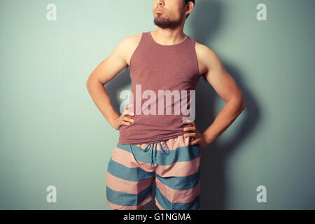 Ein junger Mann im gestreiften Shorts steht mit seinen Händen in den Hüften Stockfoto