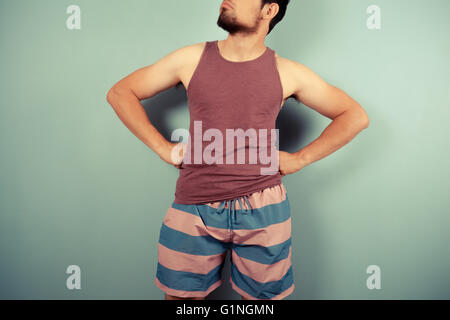 Ein junger Mann im gestreiften Shorts steht mit seinen Händen in den Hüften Stockfoto