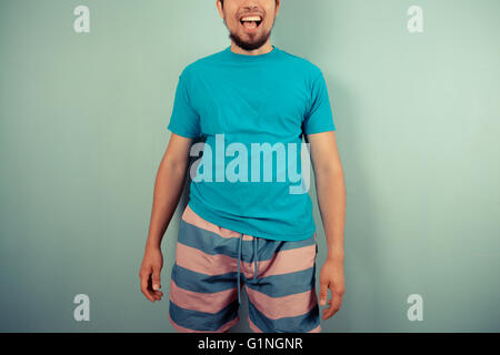 Ein glücklicher junger Mann gestreiften Shorts und ein blaues top Stockfoto