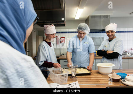 Internationale Schulklasse lernt, wie man kochen und Backen in der Lehrküche. Stockfoto