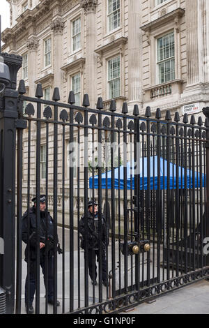 Bewaffnete Polizisten stehen hinter den Sicherheitsschleusen am Eingang zur Downing Street, London UK Stockfoto