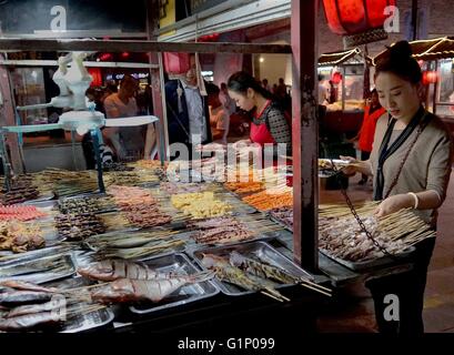(160518)--KAIFENG, 18. Mai 2016 (Xinhua)--Touristen wählen Sie ihre Favoriten vor dem Grillen in einem Nachtmarkt in Kaifeng, Zentral-China Henan Provinz, 17. Mai 2016 stehen. Kaifeng hat eine lange Geschichte von seiner berühmten Nachtmarkt, wo eine Vielzahl von Spezialitäten wie fünf-Gewürz-Brot, dampfenden Pie und Knödel sind auf den Verkauf. Am Abend verwandeln Kaifeng Straßen in Restaurants während Hunderte von Anbietern ihre Stände öffnen und Verkauf von Lebensmitteln für Menschen aus den nahe gelegenen Städten, da die Atmosphäre sehr ansprechend. Kaifeng ist historisch bekannt als Daljan, Bianliang, Bianjing, Dongj Stockfoto