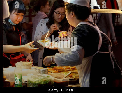 (160518)--KAIFENG, 18. Mai 2016 (Xinhua)--Leute kaufen eine traditionelle Gerichte aus der Tofo in ein Nachtmarkt in Kaifeng, Zentral-China Henan Provinz, 17. Mai 2016. Kaifeng hat eine lange Geschichte von seiner berühmten Nachtmarkt, wo eine Vielzahl von Spezialitäten wie fünf-Gewürz-Brot, dampfenden Pie und Knödel sind auf den Verkauf. Am Abend verwandeln Kaifeng Straßen in Restaurants während Hunderte von Anbietern ihre Stände öffnen und Verkauf von Lebensmitteln für Menschen aus den nahe gelegenen Städten, da die Atmosphäre sehr ansprechend. Kaifeng ist historisch bekannt als Daljan, Bianliang, Bianjing, Dongjing des Nordens Stockfoto