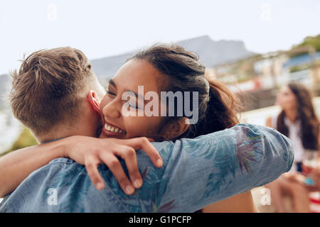 Frau Gruß ihr Freund und umarmt. Junge Frau, die ihre Freunde auf Party begrüßen. Junge Freunde Party auf dem Dach angekommen. Stockfoto