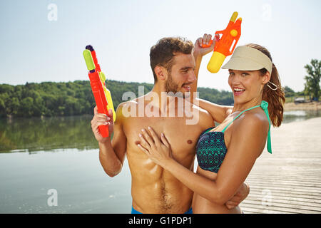 Paar an einem See Spaß mit Spritzpistolen im Sommer Stockfoto