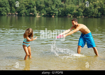 Vater und Tochter gegenseitig mit Wasser zu einem See plantschen Stockfoto