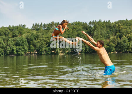 Vater im See seine Tochter ins Wasser zu werfen und Spaß im Sommer Stockfoto