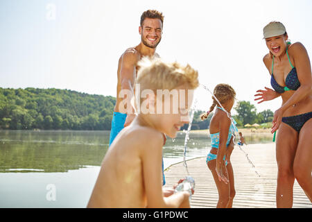 Familie Spray einander an einem See Wasser und Spaß haben Stockfoto