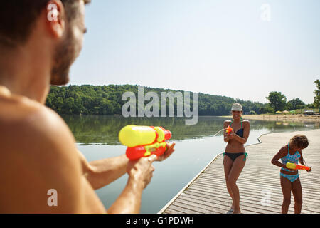 Familie sprühen Sie einander mit Spritzpistolen und viel Spaß auf ihren Sommerurlaub Stockfoto