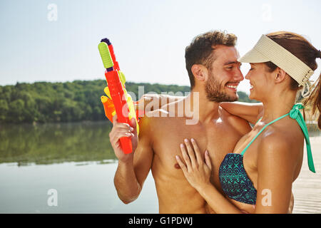 Paar in Liebe umarmt im Sommer an einem See mit Spritzpistolen Stockfoto
