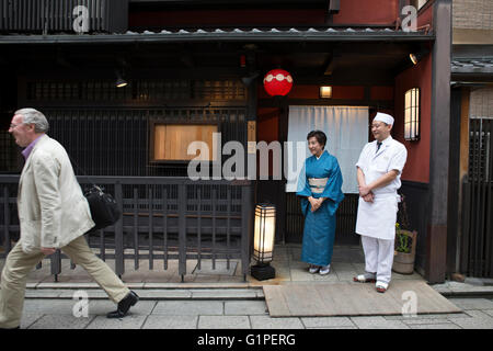 Senior japanische Gastgeberin und Köchin nach kaukasischen Kunden beobachten Stockfoto