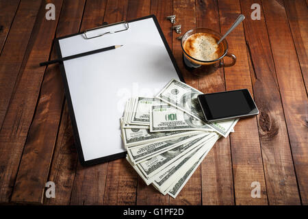 Leeres Papier, Briefkopf, Kaffeetasse, Smartphone, Bleistift und Geld auf Holztisch Hintergrund. Stockfoto