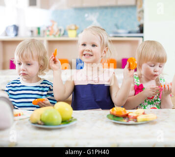 Lustige Kinder essen Orangen in Kindertagesstätte Stockfoto