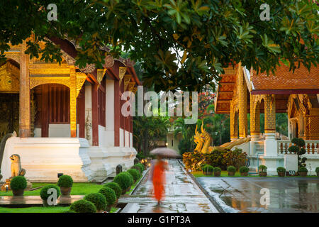 Mönch gehen unter Schirm am Wat Phra Singh Tempel, Chiang Mai, Thailand. Chiang Mai's am meisten verehrten Tempel. Stockfoto