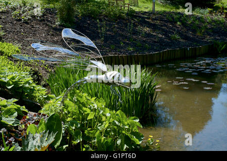 Libelle-Skulptur mit Blick auf einen Teich in Sir Harold hügeliger Gärten in Romsey England uk Stockfoto